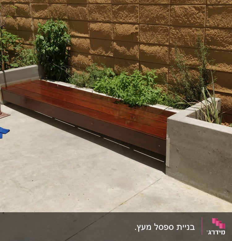 ספסל עץ ליד ערוגת צמחים עם כלי עבודה